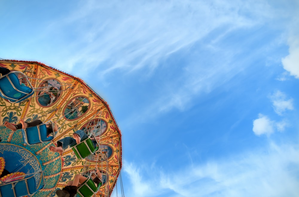 low angle photo of brown, green, and blue carousel under cloudy sky