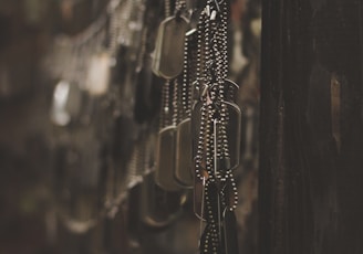 silver-colored god tags hanging on hooks shallow focus photography