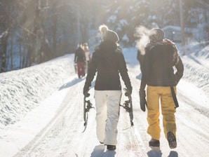 person holding snow ski blades while walking on snowy mountain during daytime