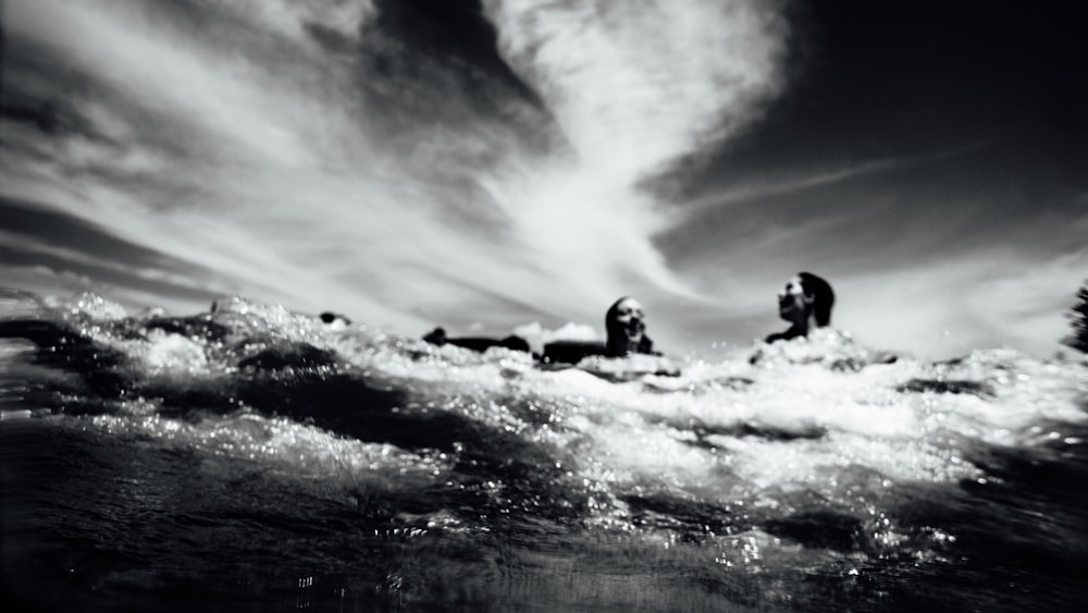Graustufenfoto von zwei Personen, die auf einem Gewässer schwimmen