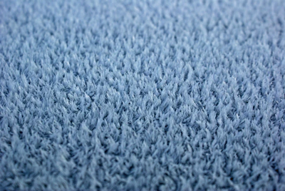 Close-up of a hand feeling the soft texture of a high-quality carpet fiber.