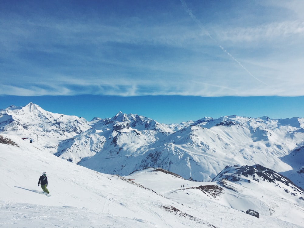 man snowboarding on mountain under cloudy sky