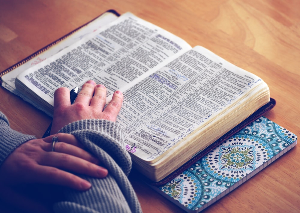 person reading a book with hands on top of book