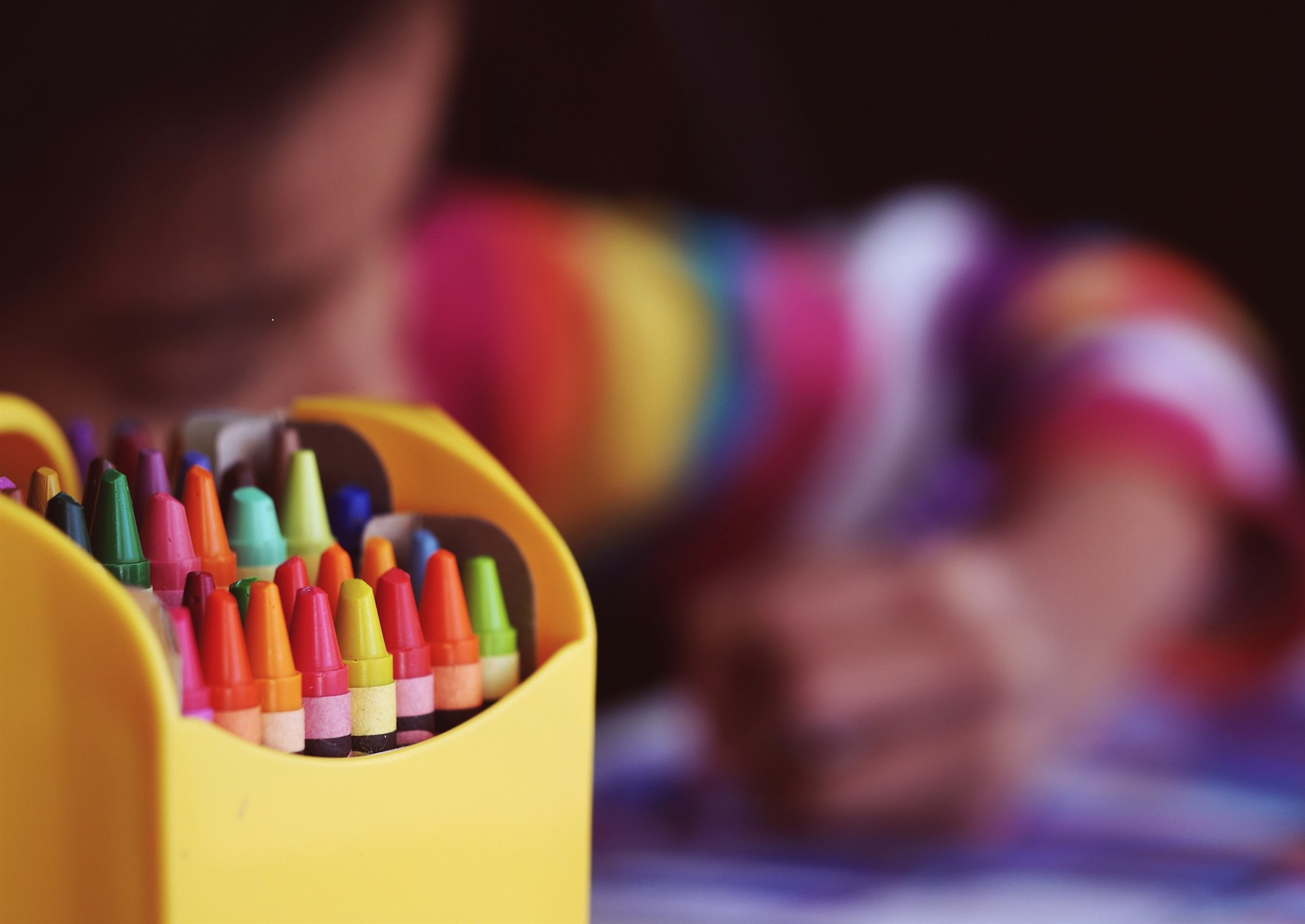 Crayons beside child coloring at daycare