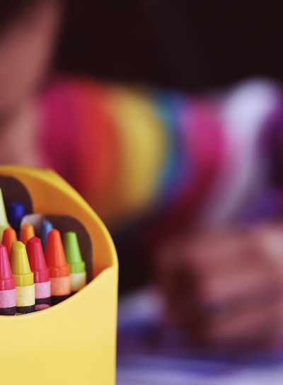 selective focal photo of crayons in yellow box