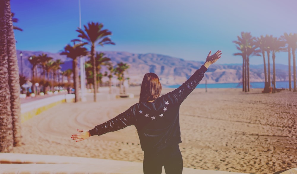 woman in black leather jacket beside beach shore during daytime