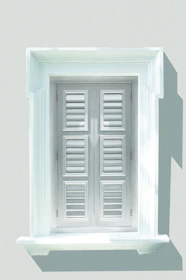 Elegant white shutters framing a sunny kitchen window with soft beige walls.