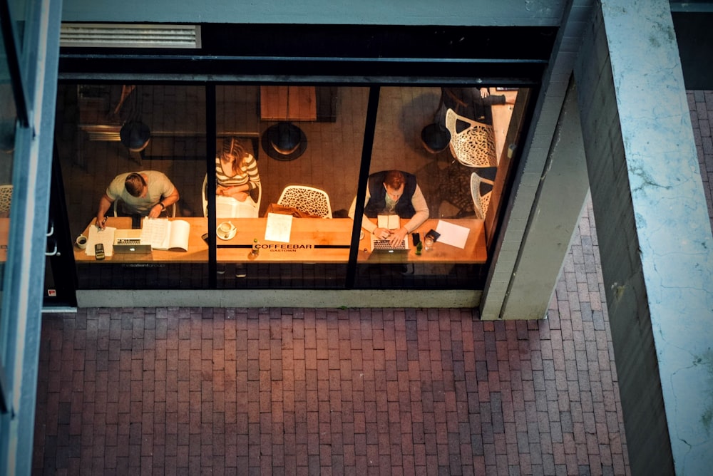 People working at their laptops in a coffee shop seen through the window