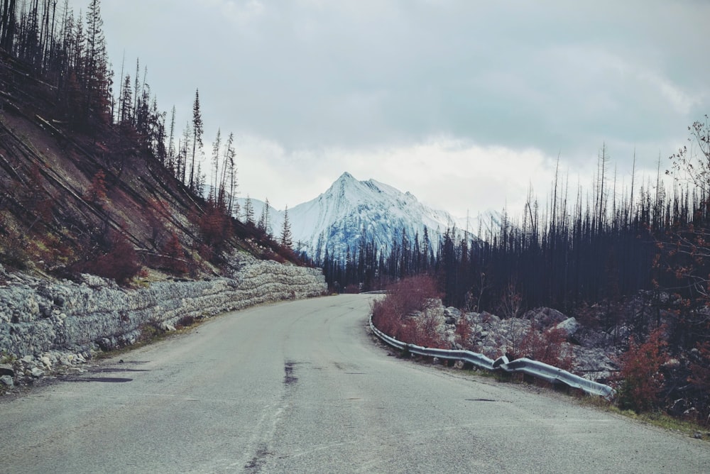 gray asphalt road towards snow covered mountain during daytime