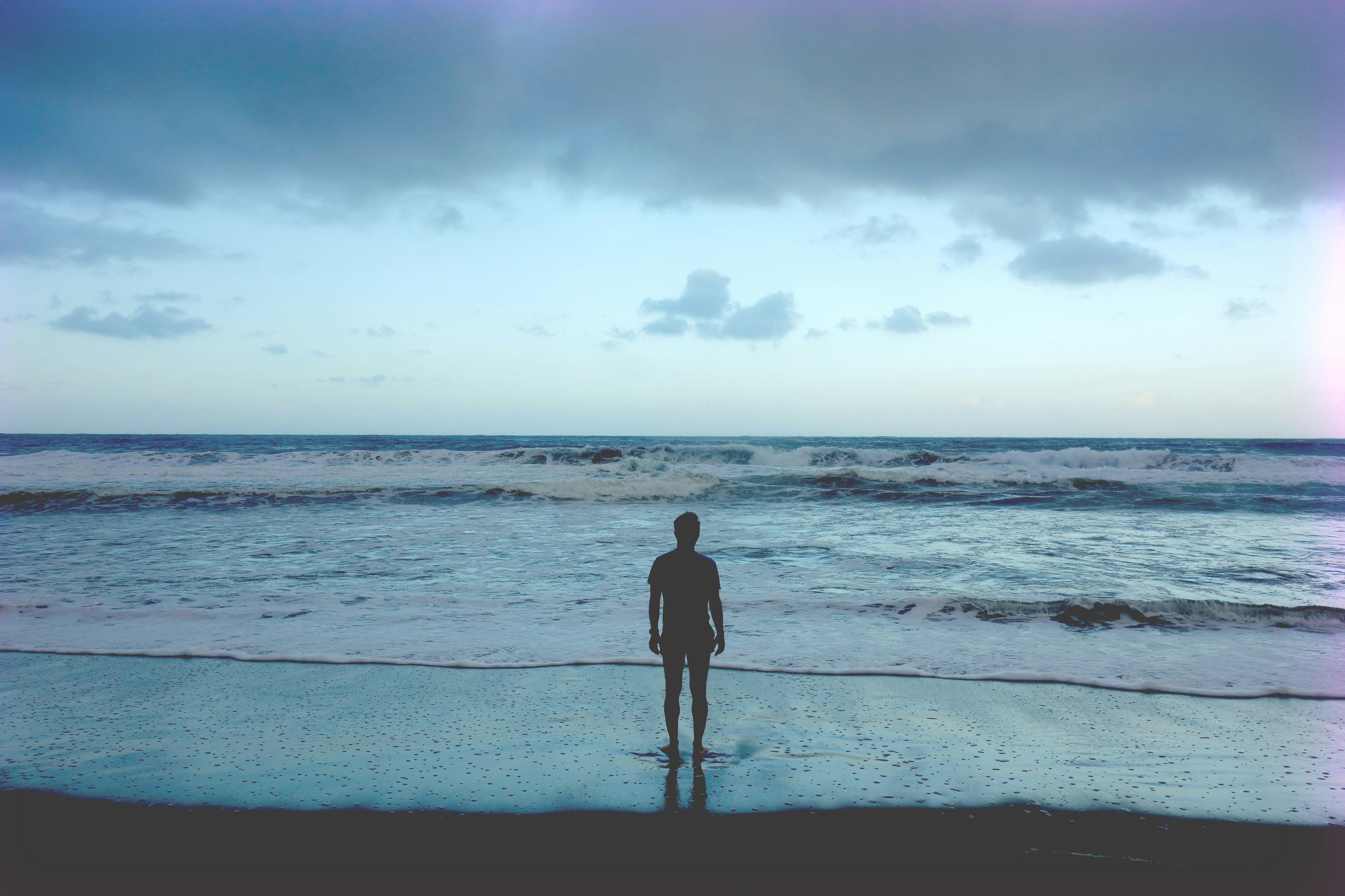 silhouette photography of man standing on seashore