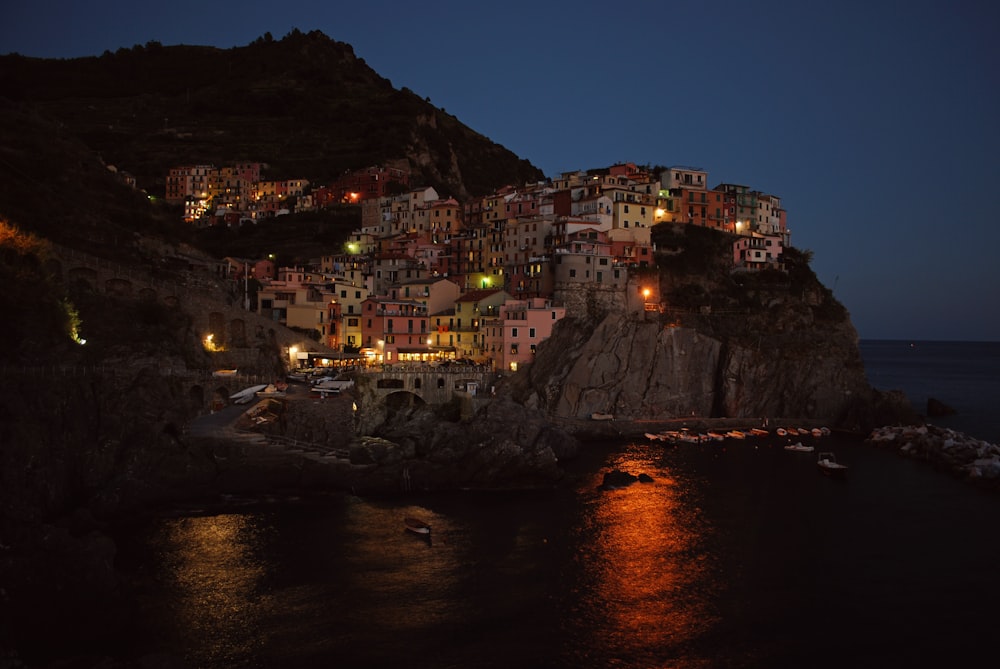 Maisons en béton sur une colline rocheuse à côté d’un grand plan d’eau pendant la nuit