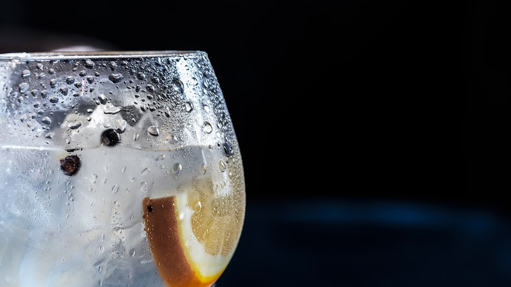 Fotografía de primer plano de copa de vino fría con bebida clara y rodaja de limón