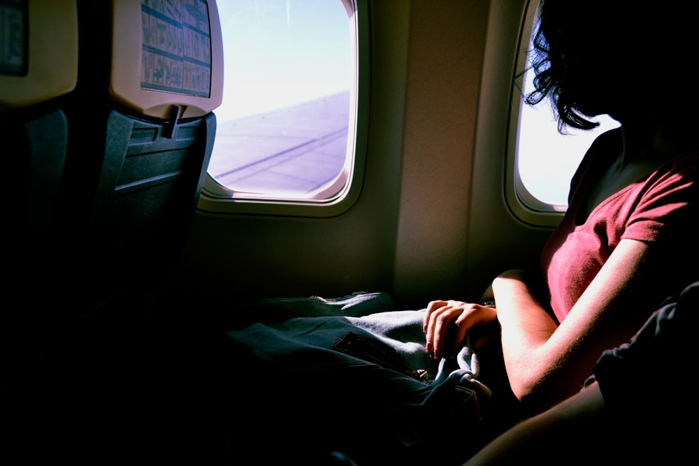Frau reitet im Flugzeug, während sie am Fenster schaut