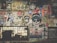 A vibrant collage of street art and posters covers a wall, featuring a mix of colorful designs, graffiti, and illustrations. Icons include skulls, cartoonish faces, animals, and various logos. The artwork is layered, with some stickers and hand-drawn images overlapping others, creating a chaotic yet artistic arrangement. Below the art, a barred window with graffiti adds to the urban aesthetic.