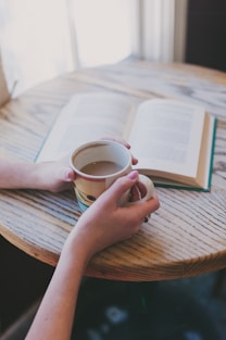 A serene morning scene with a person holding a Bible and a cup of coffee, sunlight streaming through a window.