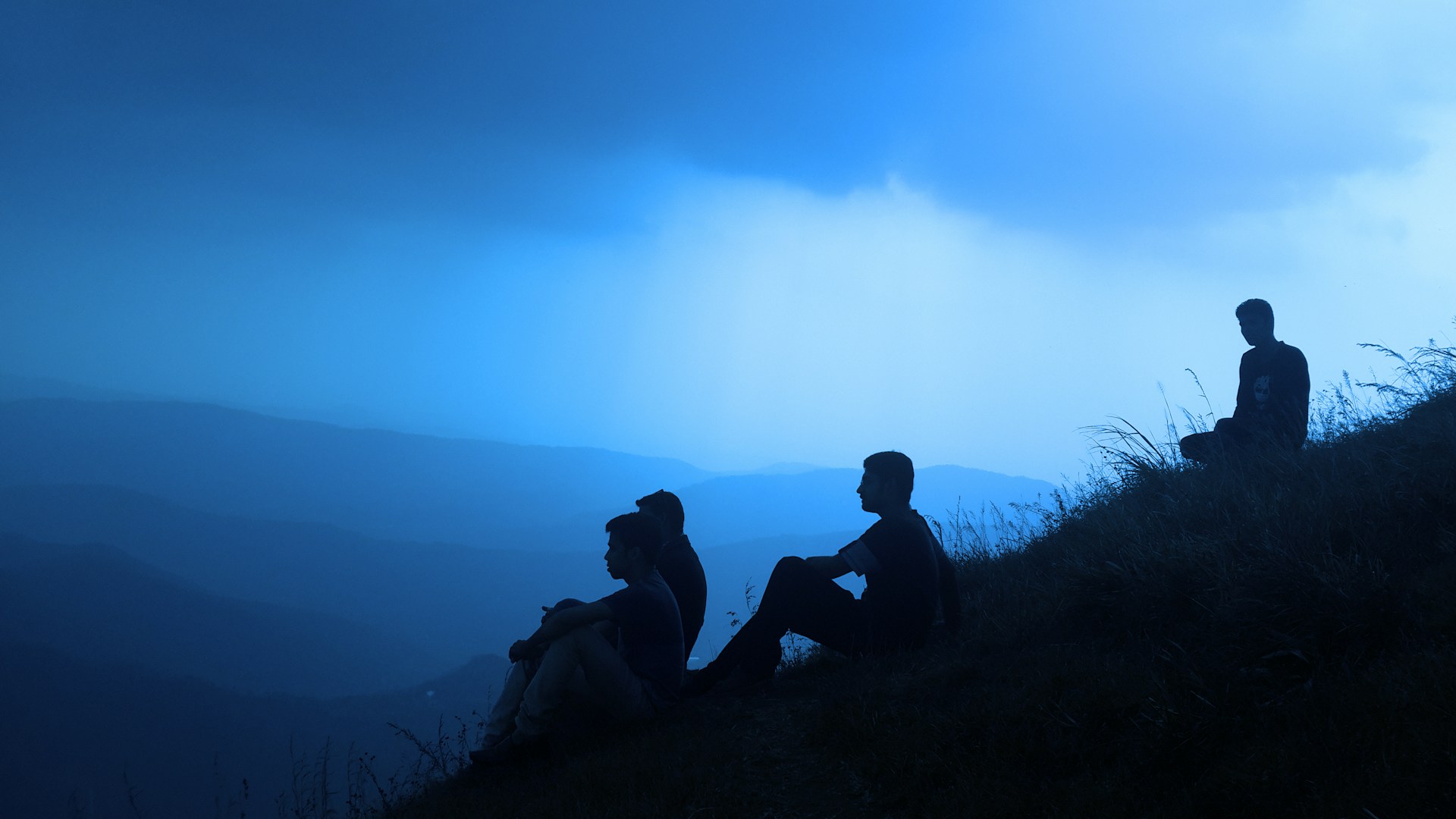 silhouette of men sitting on mountain