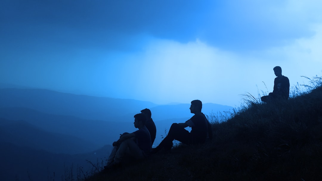 silhouette of men sitting on mountain