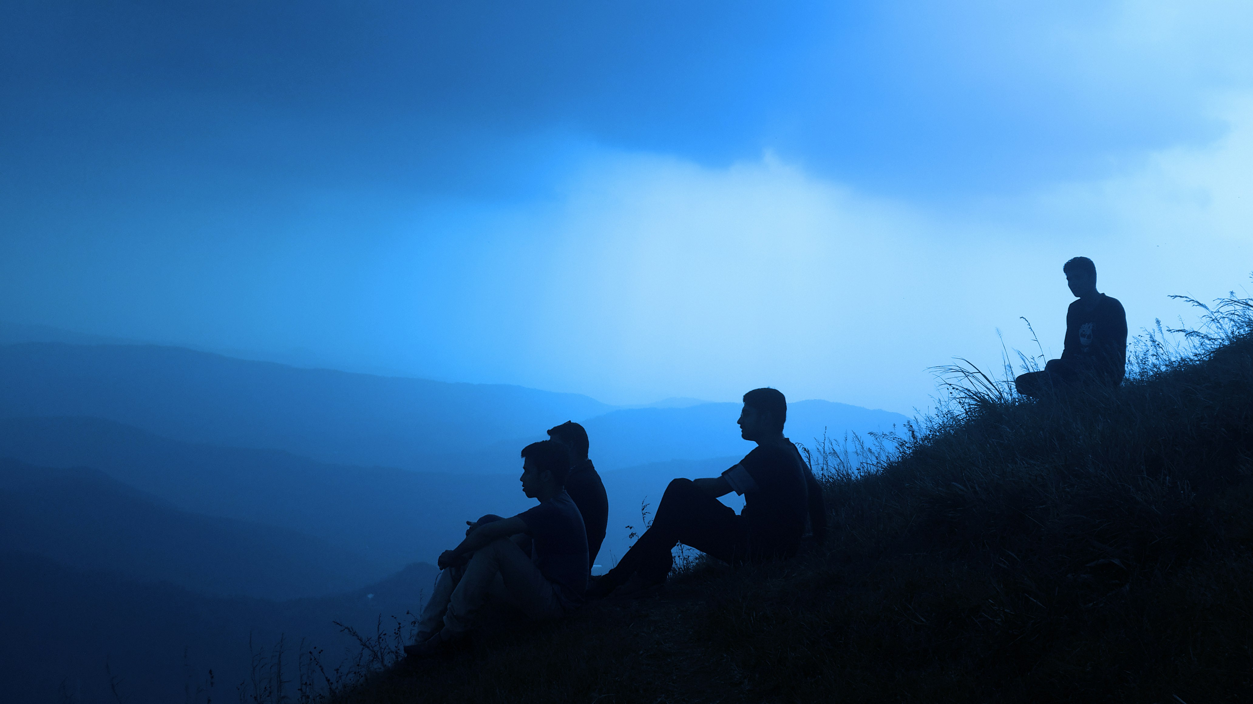 silhouette of men sitting on mountain