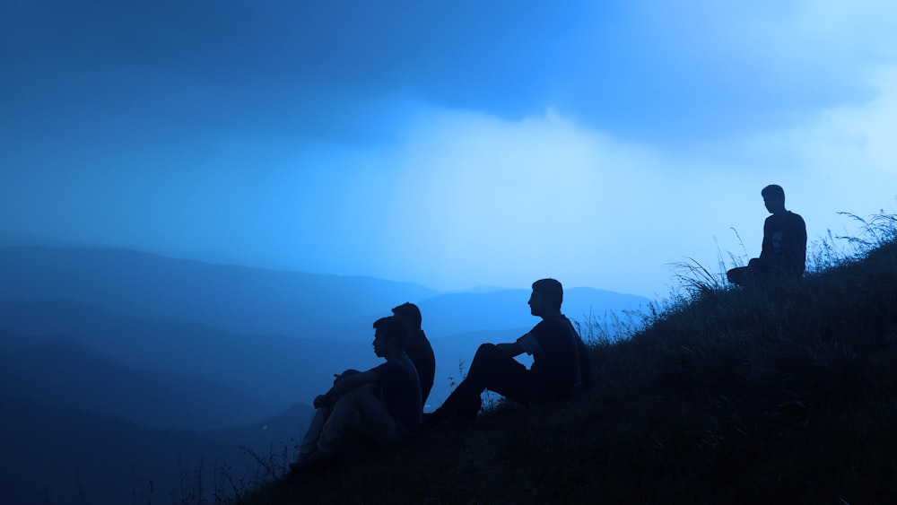 silueta de hombres sentados en la montaña