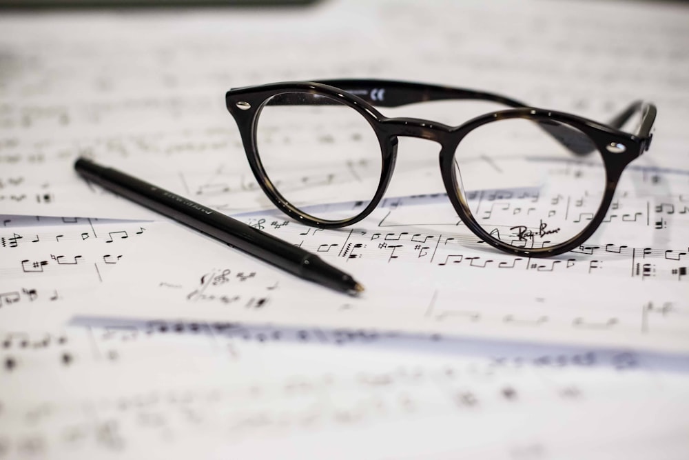 black framed panto-style eyeglasses beside black ballpoint pen