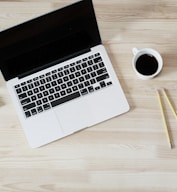 turned off MacBook Pro beside white ceramic mug filled with coffee