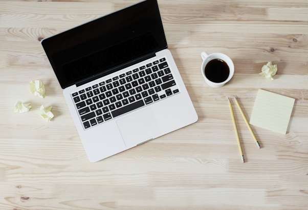 turned off MacBook Pro beside white ceramic mug filled with coffee