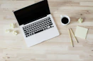 turned off MacBook Pro beside white ceramic mug filled with coffee