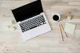 turned off MacBook Pro beside white ceramic mug filled with coffee