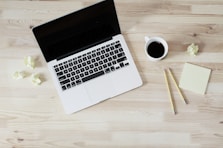 turned off MacBook Pro beside white ceramic mug filled with coffee