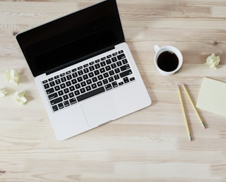 turned off MacBook Pro beside white ceramic mug filled with coffee