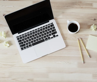 turned off MacBook Pro beside white ceramic mug filled with coffee