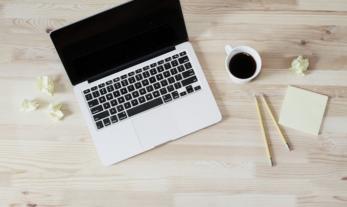 turned off MacBook Pro beside white ceramic mug filled with coffee