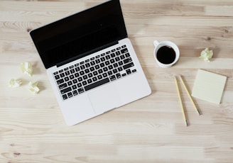 turned off MacBook Pro beside white ceramic mug filled with coffee