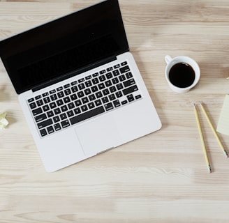 turned off MacBook Pro beside white ceramic mug filled with coffee