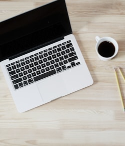 turned off MacBook Pro beside white ceramic mug filled with coffee