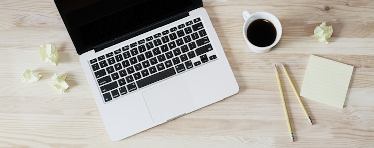 turned off MacBook Pro beside white ceramic mug filled with coffee