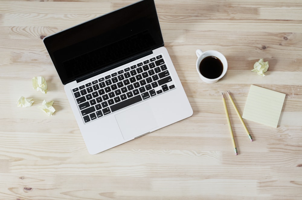 turned off MacBook Pro beside white ceramic mug filled with coffee