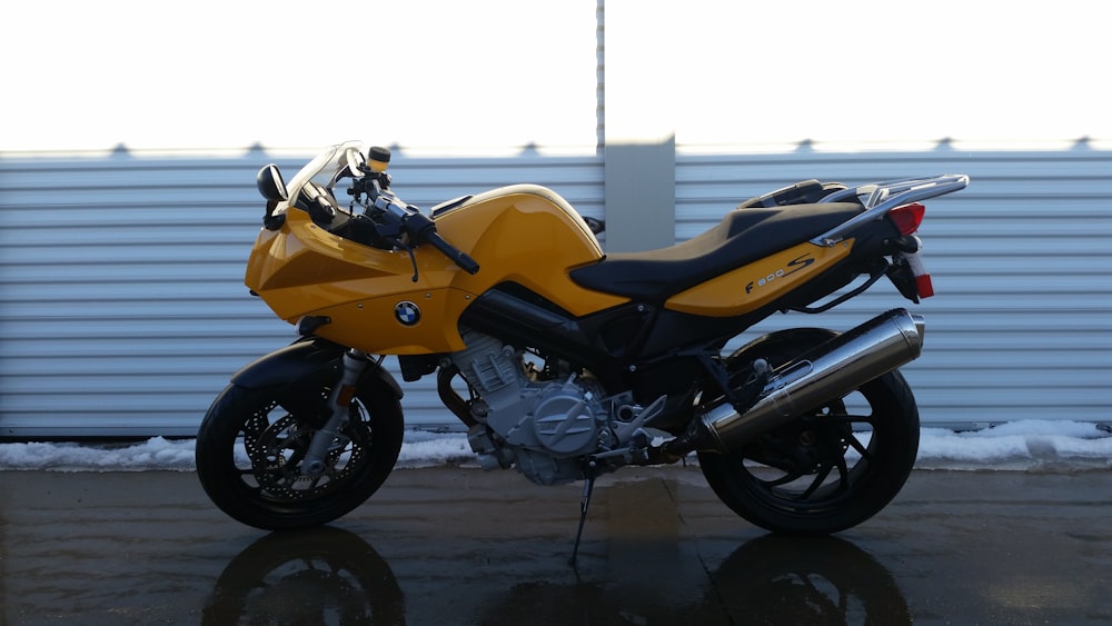 black and yellow BMW sports bike parked near white wall