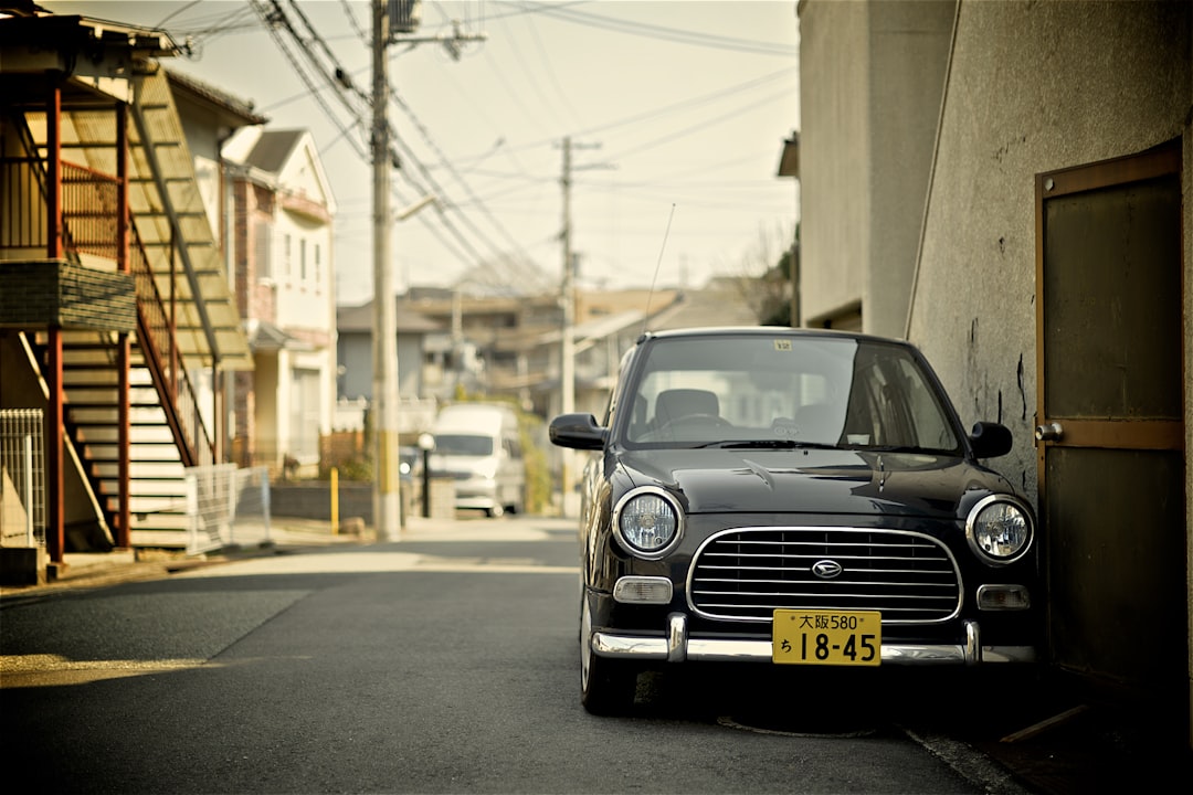 low light photography of car beside beige building, Parked black vintage car
