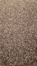 Close-up of a hand feeling the texture of a woven rug in warm tones.
