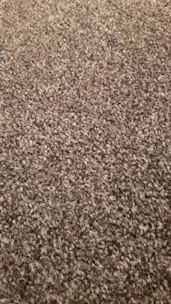 Close-up of a hand feeling the texture of a woven rug in warm tones.