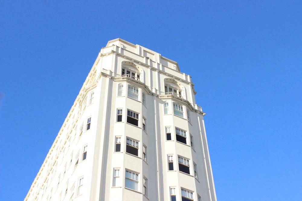 白いコンクリートの高層ビルのローアングル写真