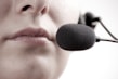 A close-up of a person's lips speaking into a black microphone headset, suggesting communication or recording.
