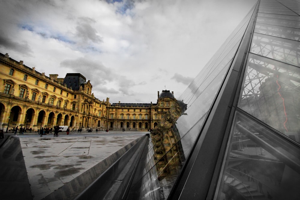 A glass window building, next to a large pavement walking in France.