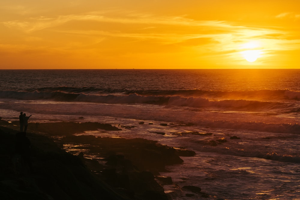 ocean waves crashing on shore during sunset