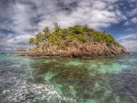 island over white clouds at daytime