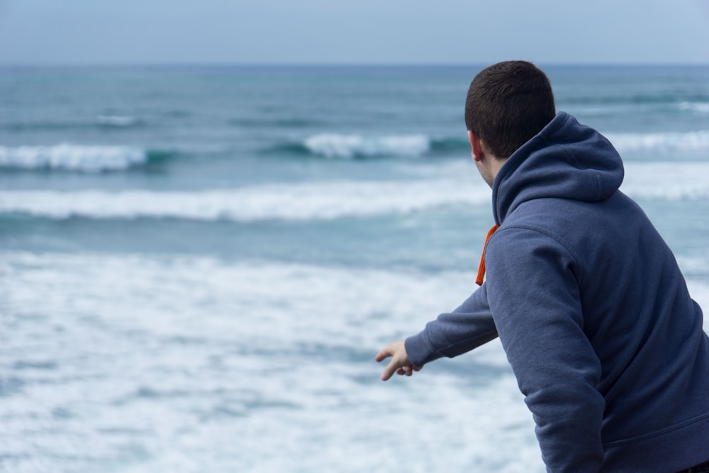 man throw pebble into the beach water