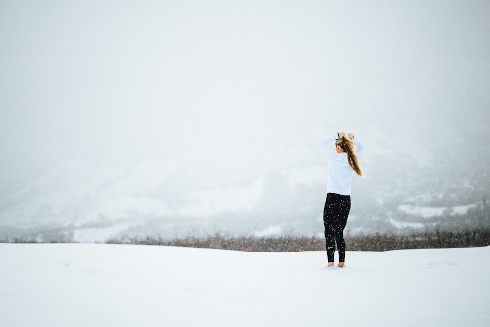 Frau steht tagsüber auf offenem, schneebedecktem Feld