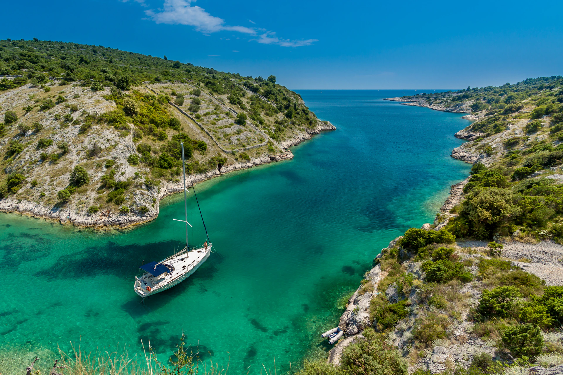 aerial photography of white boat near body of water between green mountain during daytime