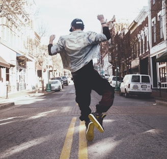 man jumping on the middle of the street during daytime